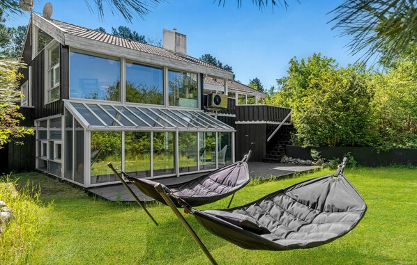 Relax in the comfort of this two-story house, featuring a spacious conservatory with a glass roof and a beautifully manicured lawn.