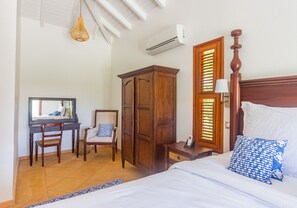 Ein Schlafzimmer mit Bett, Schreibtisch, Stuhl, Kleiderschrank und einem Fenster mit Jalousien.