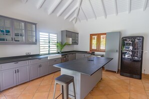 A modern kitchen with grey cabinets, a central island, and a built-in refrigerator.