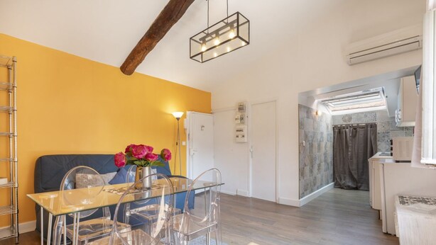 A modern kitchen with a built-in oven, a dining area with a glass table and chairs, and a yellow accent wall. - Old Nice- Jean Jaurès FSHH (NICE)