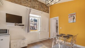 A modern kitchen with a built-in oven, microwave, and refrigerator. There's a dining area with a glass table and chairs, and a large window offering a view of the city. - Old Nice- Jean Jaurès FSHH (NICE)