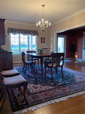 A dining room with a chandelier, wooden table, chairs, and a large floral rug.