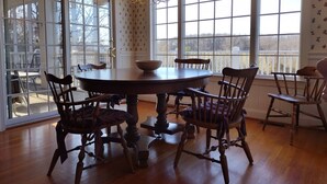 A dining area with a round table, six wooden chairs, a chandelier, and large windows with a view. - Quiet, Spacious House Close to SML and Liberty University (Moneta)