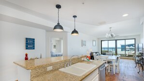 A modern kitchen with granite countertops, a double sink, and pendant lighting. - Beach Paradise - Perfect Ocean Sunset Views with Pool & Sauna & Breakfast! (Mexico Beach)