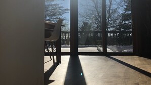 Ein Zimmer mit großen Fenstern, Holzboden und einem Sessel.