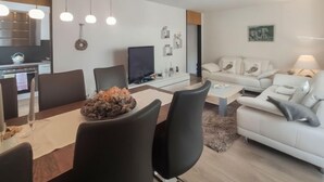 A modern living room with a dining area, a sofa set, and a flat-screen TV. - Allod Park Haus C 207 by Interhome (Davos)