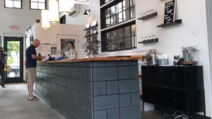 Eine Bar mit einer Theke, hängenden Lampen und Regalen mit Gläsern.