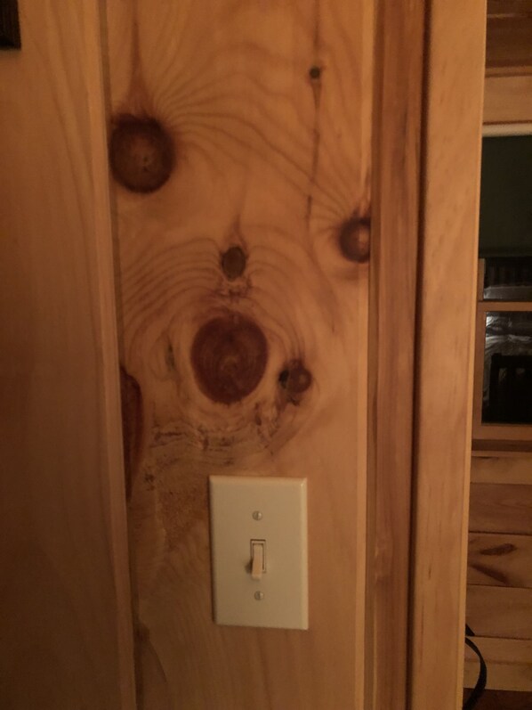 A wooden door with a light switch and a visible electrical outlet.