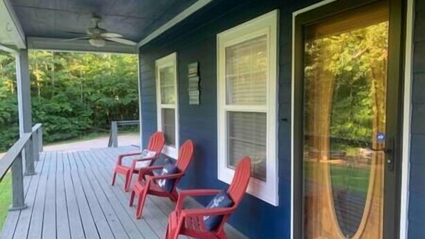 Een overdekte veranda met een houten terras en twee rode stoelen.