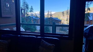 A room with a large window overlooking a mountain landscape, a wooden deck outside, and a view of other buildings. - 0.5 mile walk to Gondola and Keystone Village!  50 yards to Keystone Shuttle!   (Keystone)