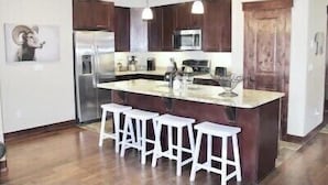 A modern kitchen with a central island, bar stools, stainless steel appliances, and dark wooden cabinets. - 0.5 mile walk to Gondola and Keystone Village!  50 yards to Keystone Shuttle!   (Keystone)