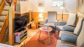 Ein gemütliches Wohnzimmer mit Fernseher, Kamin und bequemen Sitzmöglichkeiten.