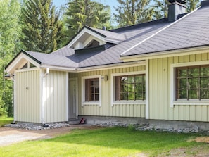 Een gelijkvloers huis met een puntige dakkapel, een voortuin en een kleine garage.