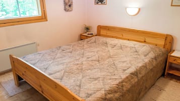Ein Schlafzimmer mit einem hölzernen Bett, einem Nachttisch mit einer Uhr und einem Fenster mit Jalousien.