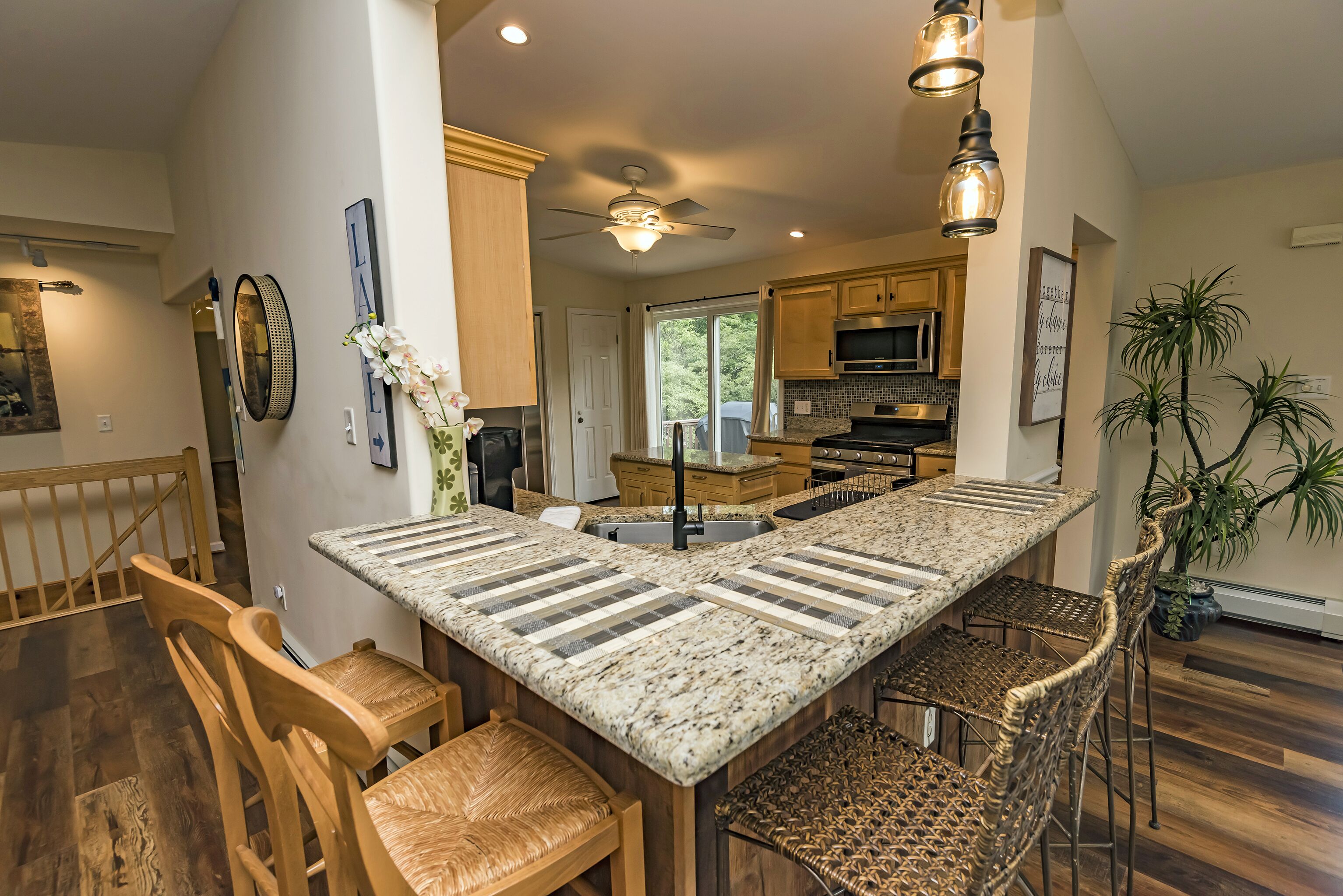 A spacious kitchen with a large island, wooden chairs, and a ceiling fan.