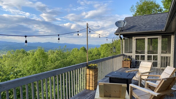 A wooden deck with outdoor furniture, a satellite dish, and a scenic view of mountains and trees.