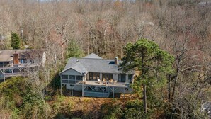 A two-story house with a balcony overlooking a forested area.