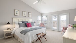 A bedroom with a large bed, a nightstand, a chair, and a dresser.