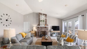 A living room with a fireplace, sofas, a coffee table, and a TV.