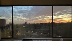 Una stanza con un'ampia finestra vista paesaggio al tramonto, con un tavolo e due sedie.