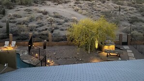 Un'area patio con piscina, sedie a sdraio e vista su un paesaggio collinare.