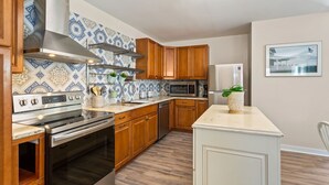 Una cocina con armarios de madera, una campana extractora de acero inoxidable, un microondas y un refrigerador.