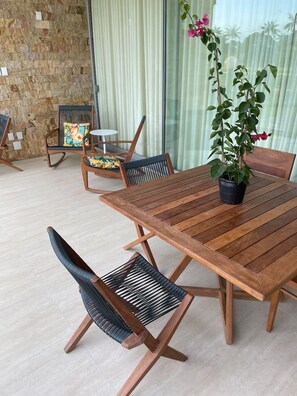 Enjoy dining al fresco in this outdoor space with a wooden table and chairs, a potted plant, and a small round table.