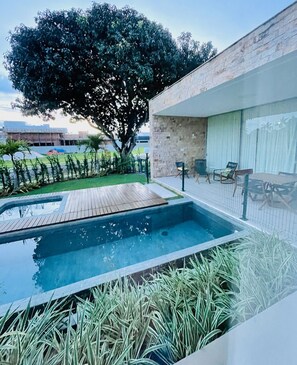 Relax by the pool surrounded by a lush lawn and a distant sports field view.