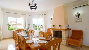 Una sala da pranzo con camino, sedie in legno e un lampadario.