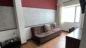A modern living room with a brown sofa, a small table, and a TV. - Hotel Florencia Plaza (Medellín)
