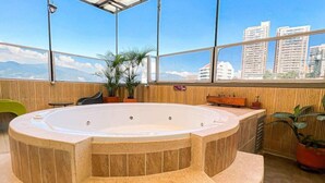 A hot tub in a room with large windows, wooden walls, and potted plants. - Hotel Florencia Plaza (Medellín)