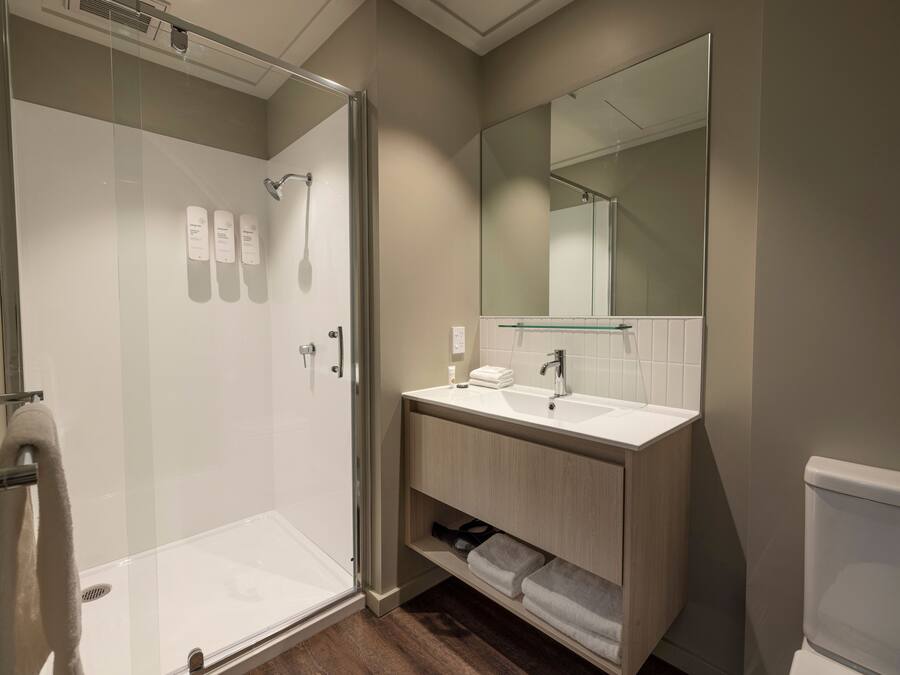 Une salle de bain moderne avec une douche à parois de verre, un lavabo blanc et un grand miroir.