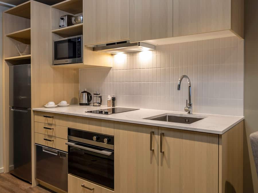Cocina compacta con microondas, estufa, horno y lavamanos.