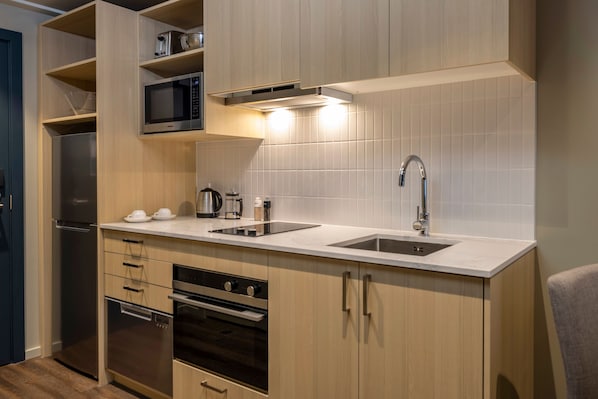 Cocina compacta con microondas, estufa, horno y lavamanos.