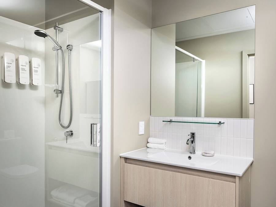 Un baño moderno con cabina de ducha de vidrio, un lavabo blanco y un espejo grande.