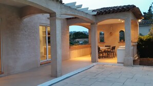 A covered patio area with a table and chairs, a sliding glass door leading to an interior space, and a view of the surrounding landscape. - Villa for 8 people, 16 minutes' walk from the beaches and town center of Ste Maxime (SAINTE MAXIME)