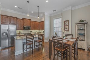 A modern kitchen with wooden cabinets, stainless steel appliances, and a central island with chairs.