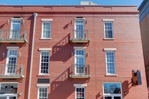 A red brick building with multiple windows and balconies, some with railings.