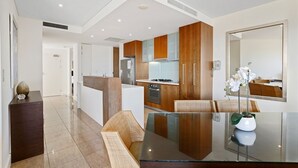 Una cocina moderna con armarios de madera, una isla central y un comedor con mesa de vidrio.