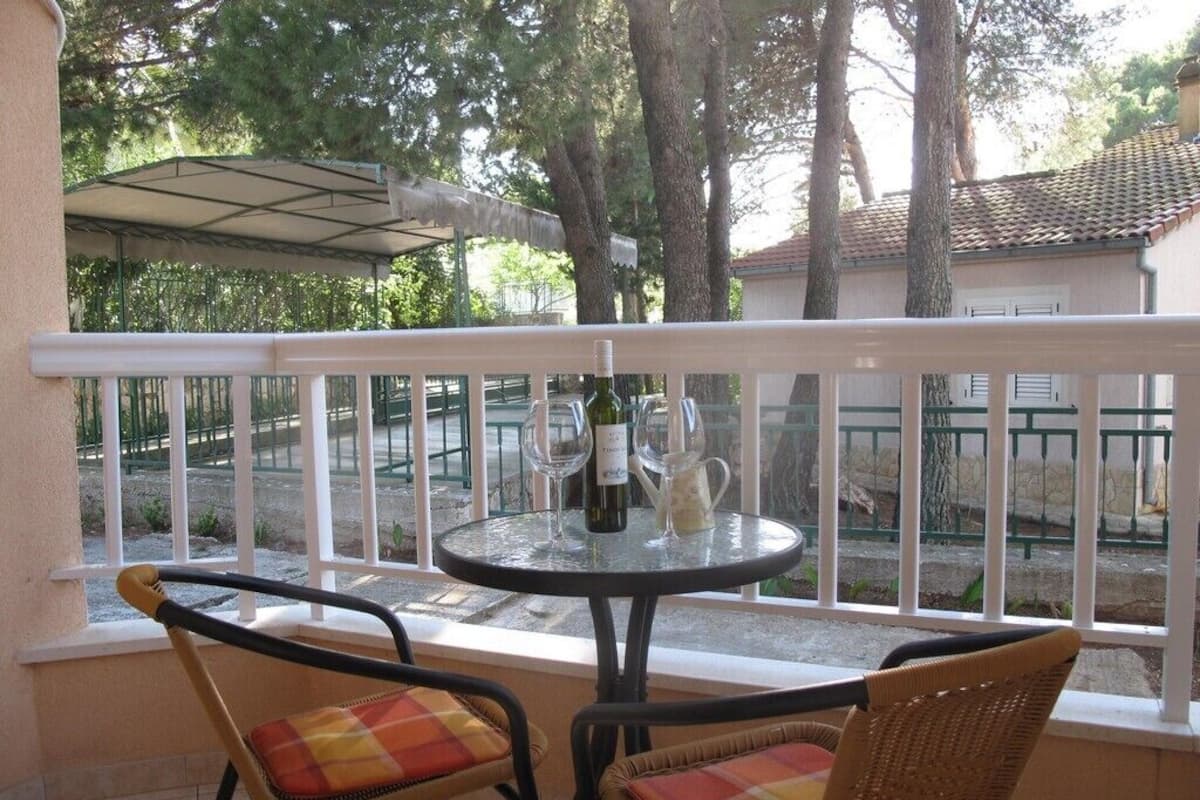 A balcony with a table, chairs, and a bottle of wine.