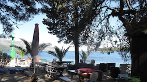 Un espace extérieur aménagé avec des tables et des chaises, une poubelle et une vue sur la mer.