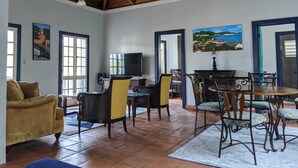 Un amplio salón con techo de madera alto, un comedor con mesa y sillas, y un sofá.