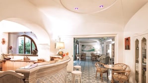 A spacious room with a curved ceiling, a dining area with wicker chairs, and a bar area with stools. - Hotel Terme Oriente Beach & SPA (Ischia)