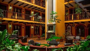 A hotel lobby with a central seating area, multiple balconies, and a variety of plants. - Catedral Hotel (San Cristóbal de las Casas)