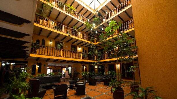 A multi-level atrium with balconies, seating areas, and potted plants. - Catedral Hotel (San Cristóbal de las Casas)