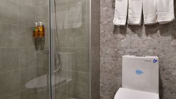 Habitación cuádruple Deluxe | Baño | Ducha, cabezal de ducha tipo lluvia, secador de pelo y zapatillas