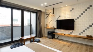 Un dormitorio moderno con un ventanal grande, un televisor de pantalla plana montado en una pared con textura, un banco de madera y una mesita de noche pequeña.