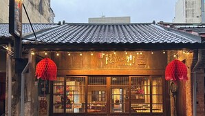 Un edificio tradicional con techo de tejas y puertas de madera, con letreros y faroles decorativos.