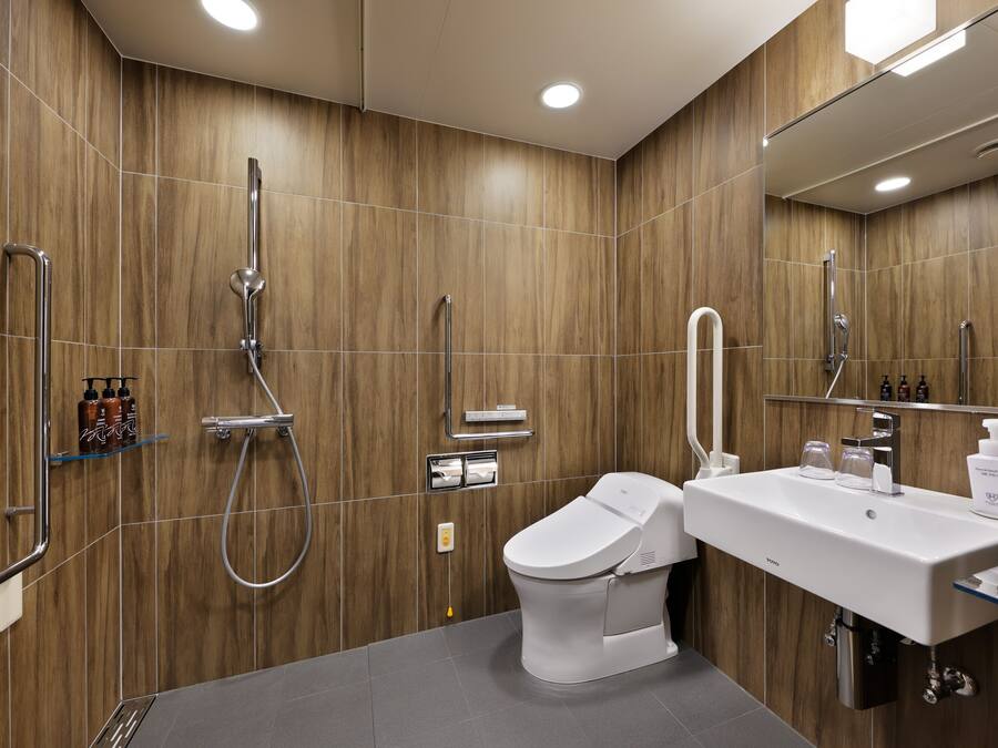 Un baño moderno con pared de madera, inodoro blanco, lavamanos y zona de ducha.