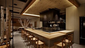 Una cocina moderna con una isla central, taburetes de bar, sillas de madera y un horno empotrado.